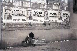 Niña indigente ante carteles pidiendo el voto en las elecciones constituyentes del 15 de junio d...
